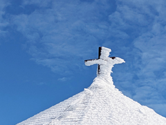 eingeschneites Kreuz auf Kirchendach