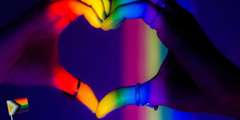 Herz geformt aus zwei Händen, in Regenbogenfarben angeleuchtet