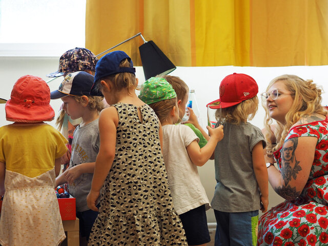 Eine Studentin spricht mit einer Gruppe Kindern.
