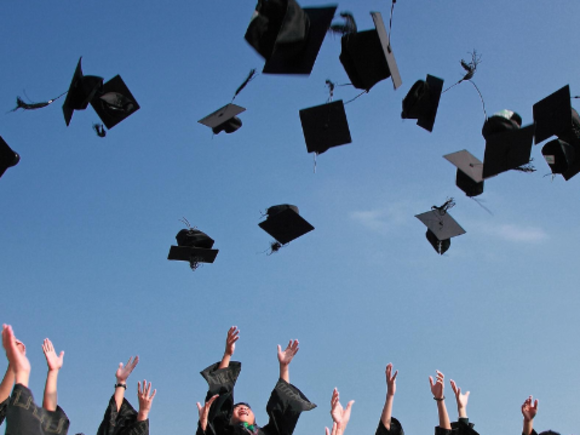 MRMA Masterfeier Alumni werfen Hüte in die Luft MRMA Logo am unteren Bildrand