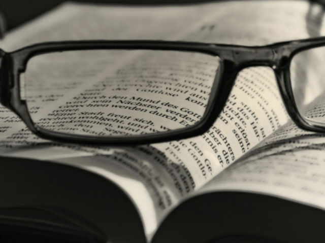 Eine Brille liegt auf einem augeschlagenen Buch