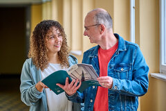 Zwei Mitarbeitende der KHSB blättern in dem Rechenschaftsbericht der Hochschule