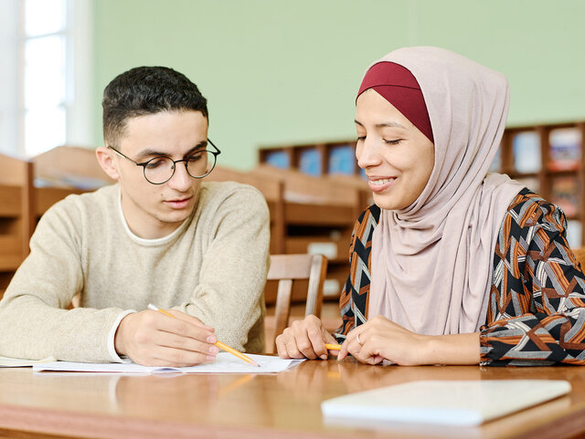 Mann unterstützt Frau beim Ausfüllen oder Lesen eines Formulars