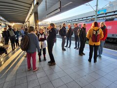 Eine Gruppe der Hochschulangehörigen wartet auf einem Bahnsteig.