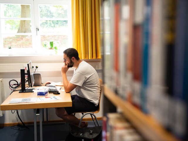 Ein Student sitzt an einem der PC Arbeitsplätze in der Bibliothek.