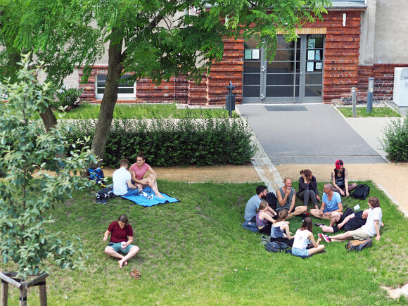 Studierende sitzen im Gras im Innenhof der KHSB.