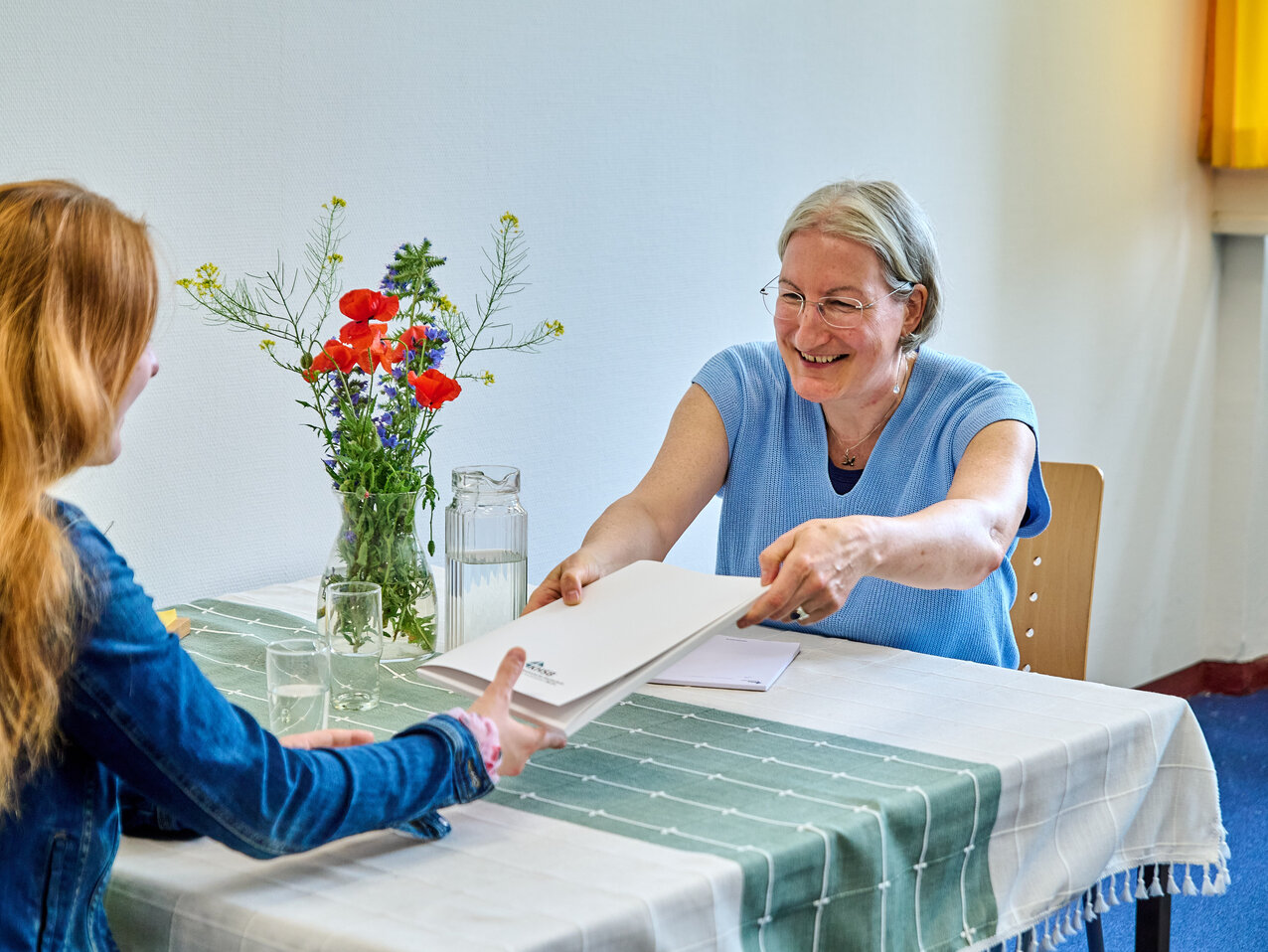 Zwei Personen sitzen sich gegenüber an einem Tisch. 