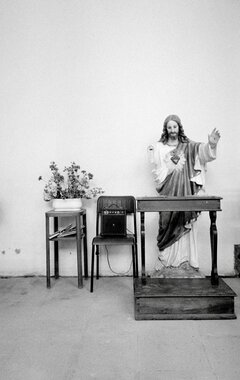 Symbolbild: Jesus-Statue mit Blumen und einem Verstärker