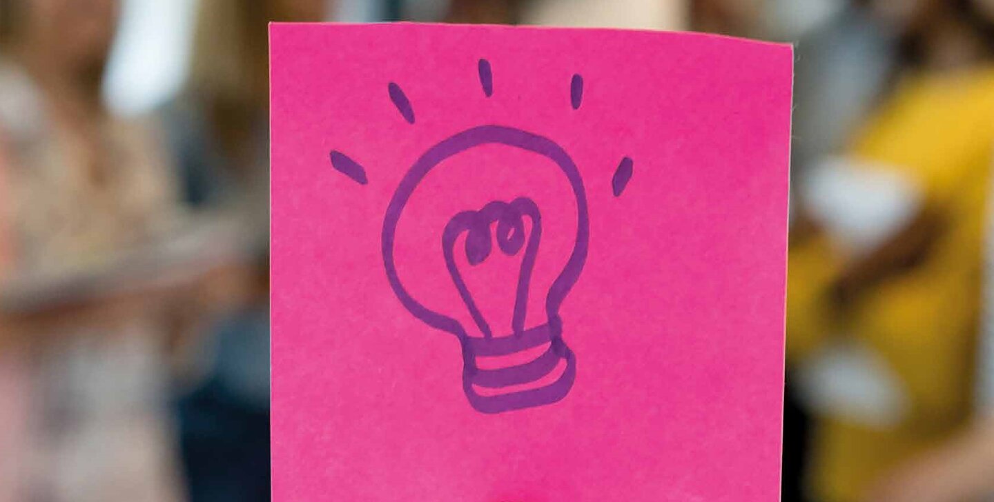 Haftnotiz in kräftigem Pink vor unscharfer Menschenmenge