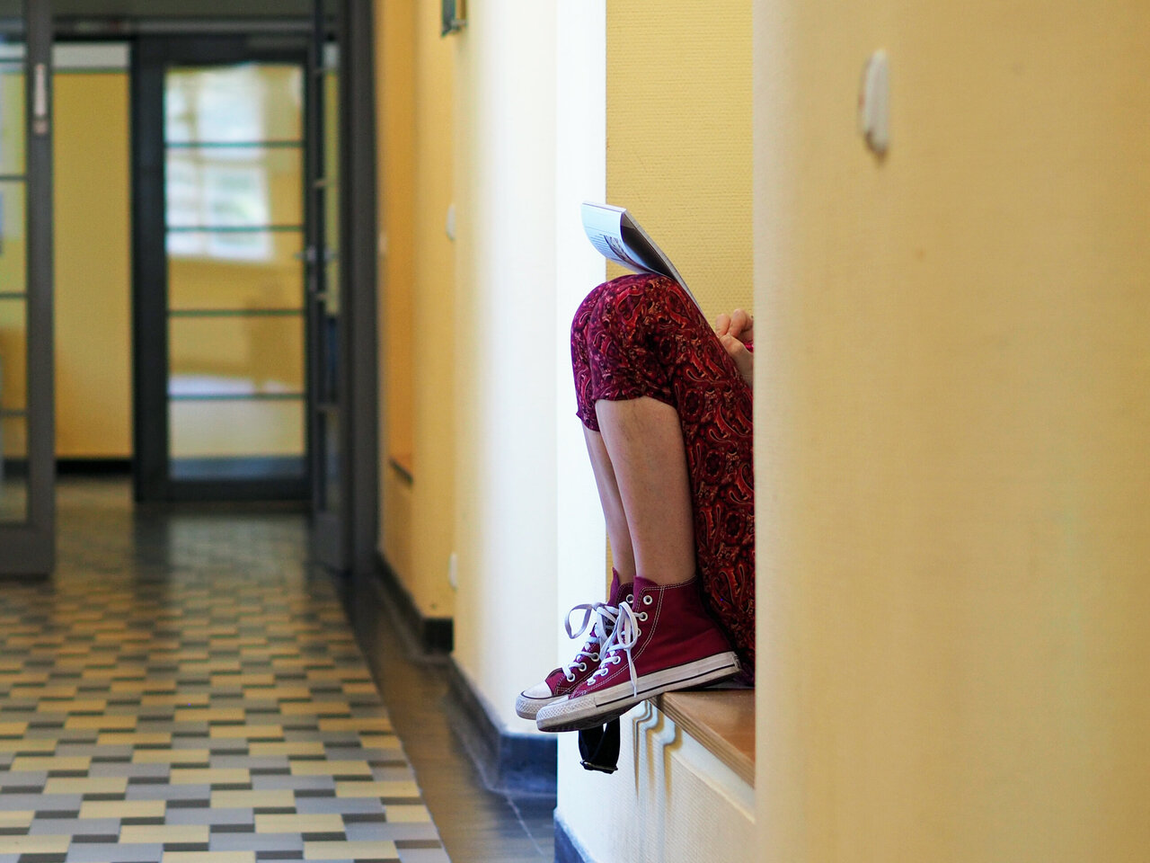 Eine Person sitzt im Flur der KHSB in einer Nische.