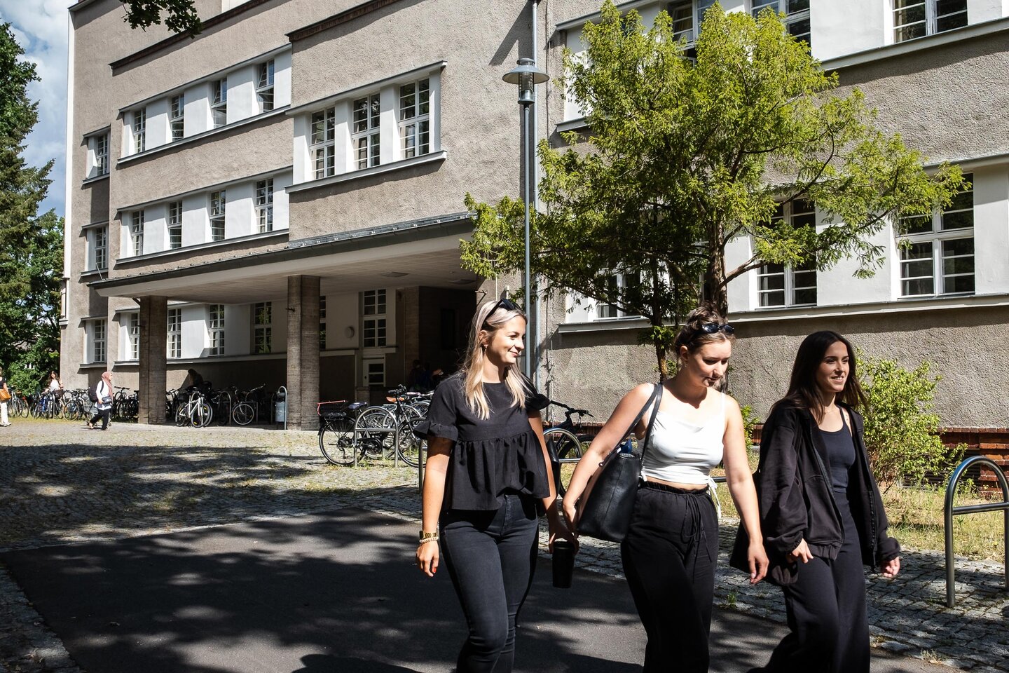Studierende laufen am Hochschulgebäude vorbei