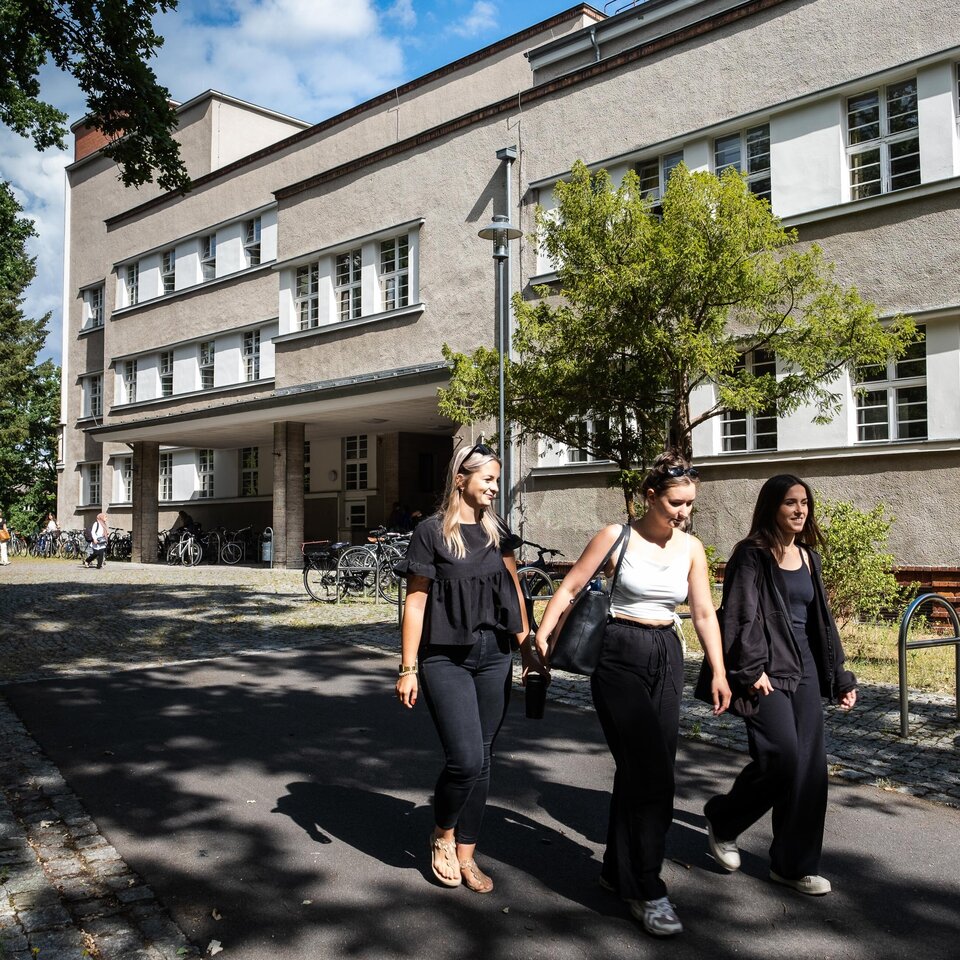 Studierende laufen am Hochschulgebäude vorbei