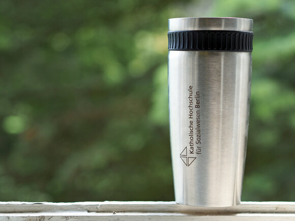 Ein Thermosbecher mit dem Logo der KHSB. 