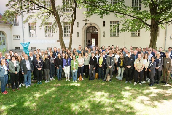 Gruppenbild der rund 70 Teilnehmenden auf einer grünen Wiese im Halbschatten.