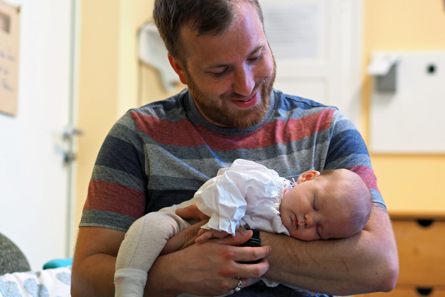 Ein Student hält sein schlafendes Baby im Arm. 