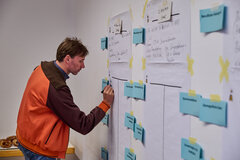 Ein Workshop-Teilnehmender notiert etwas auf einer großen Pinnwand mit Ideen.