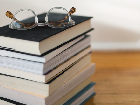 Bücherstapel mit einer daraufliegenden Brille