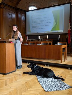 Sozialpädagogin Ann-Christin Feist berichtet über Tiergestützte Aktivitäten bei Ihrem Träger My Way Soziale Dienste, während Hund Max sie aufmerksam begleitet.