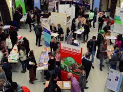 Viele Stände und Tische in der Aula sind mit Menschen umlagert.