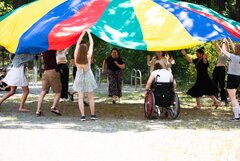 Eine Seminargruppe hält gemeinsam ein großes Schwingtuch hoch.