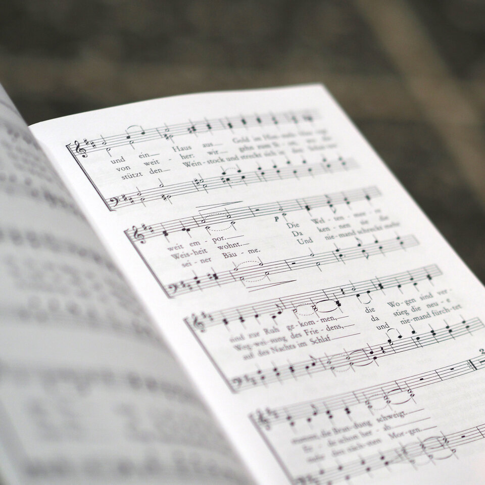 Jemand hält ein Heft mit Musiknoten in der Hand.