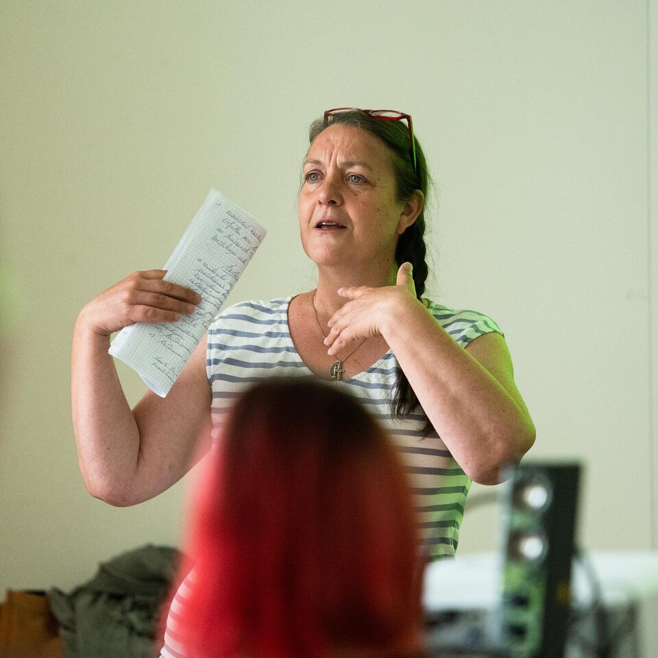 Eine Person steht vor der Seminargruppe und gestikuliert mit den Händen.