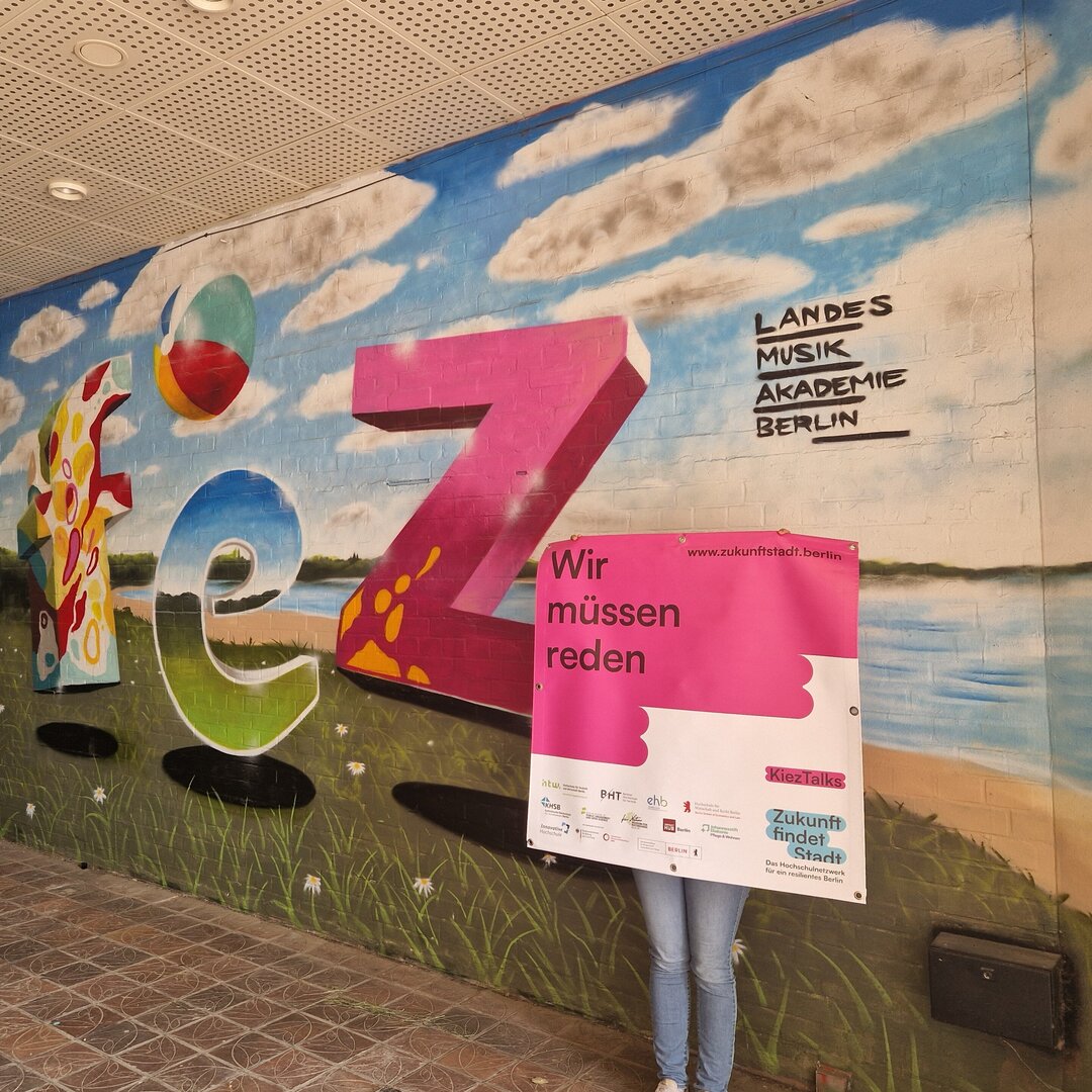 kieztalks Eine Person hält ein großes Banner mit der Aufschrift "Wir müssen reden."
