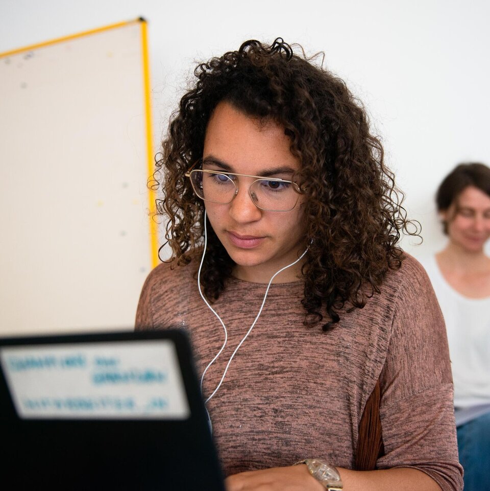 Studentin arbeitet am Laptop mit Kopfhörern