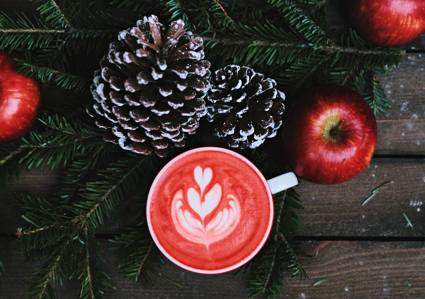 Tasse im weihnachtlichen Ambiete mit Äpfeln und Tannenzapfen