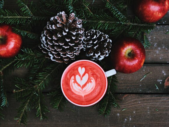 Tasse im weihnachtlichen Ambiete mit Äpfeln und Tannenzapfen