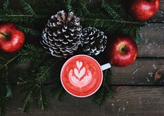 Tasse im weihnachtlichen Ambiete mit Äpfeln und Tannenzapfen