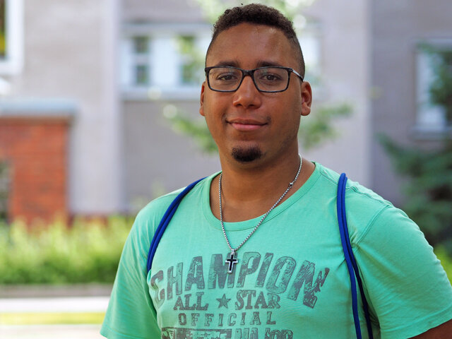 Ein Student steht im Innenhof der KHSB und lächelt. 