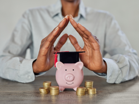 Hände bilden symbolisches Dach über Sparschwein