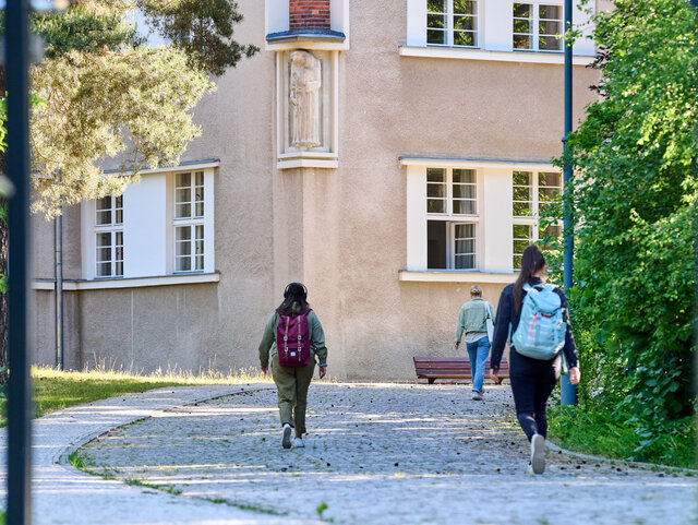 Studierende gehen die Einfahrt zur KHSB entlang.