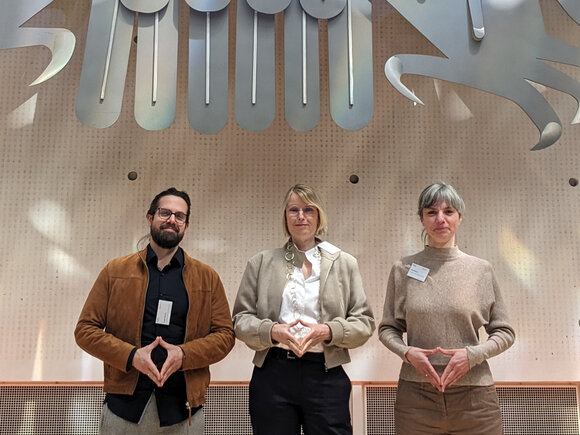 Gewinne-Projektleitung und Mitarbeite*innen vor dem Bundesadler im Plenarsaal in Bonn