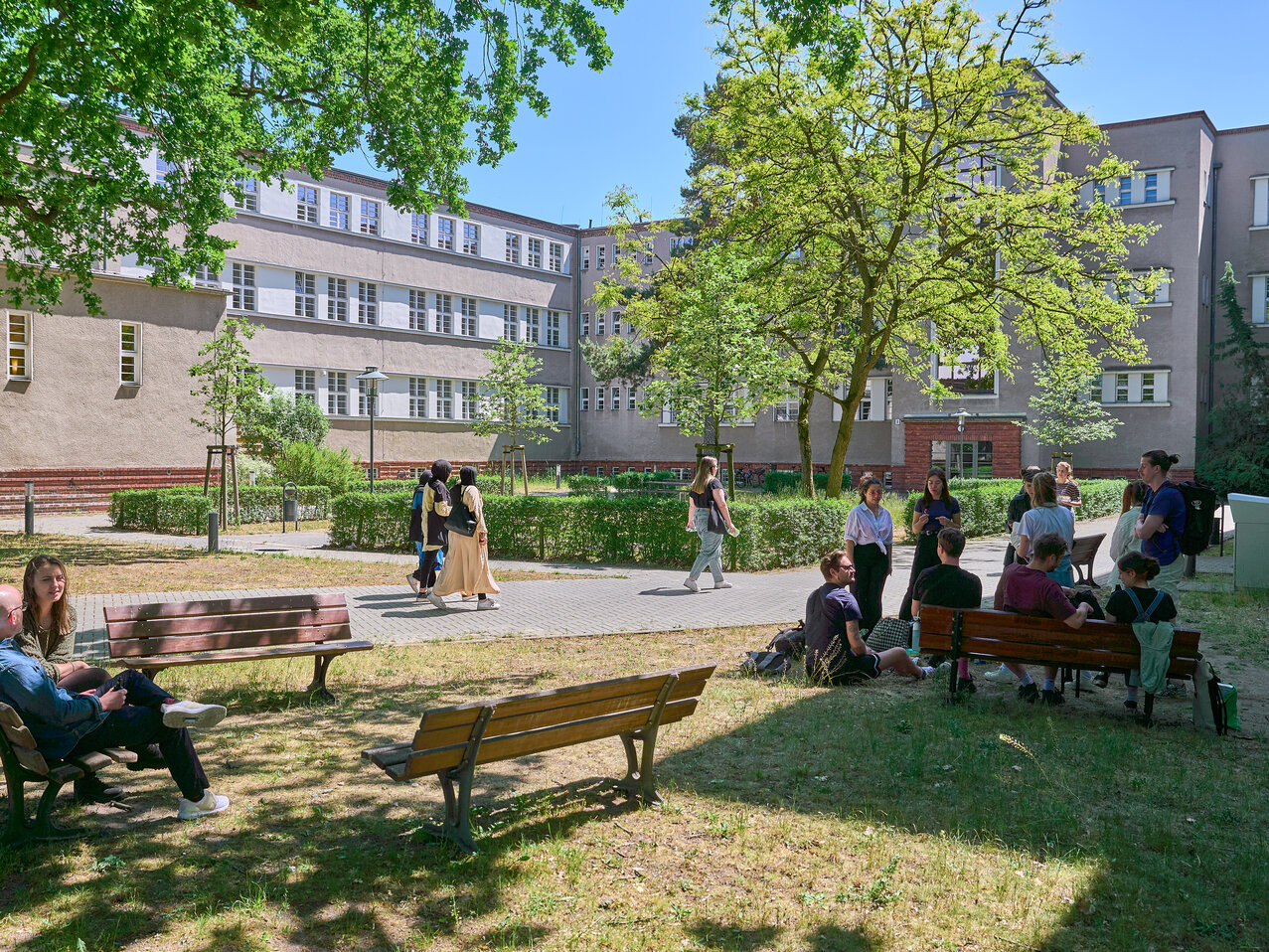 Der grüne Innenhof der KHSB mit Studierenden, die sich unterhalten. 