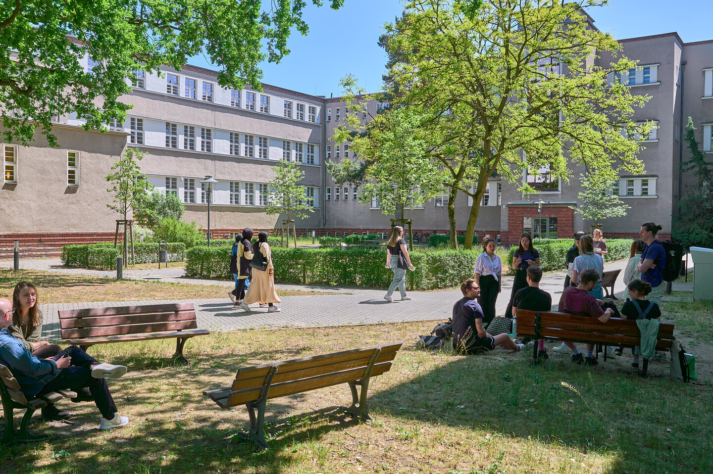 Der grüne Innenhof der KHSB mit Studierenden, die sich unterhalten. 