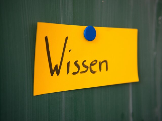 Eine Moderationskarte mit der Aufschrift "Wissen" hängt an der Tafel.