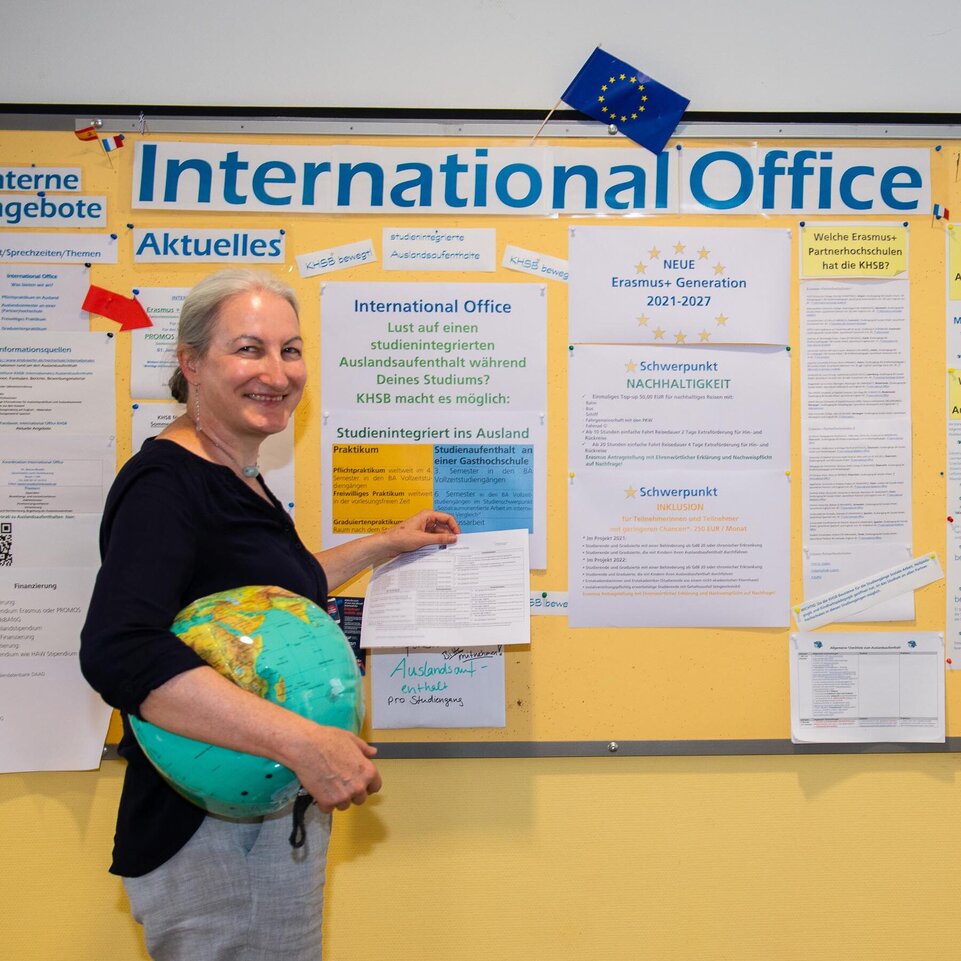 Dr. Marion Bonillo bringt einen Aushang an der Pinnwand des International Office an.