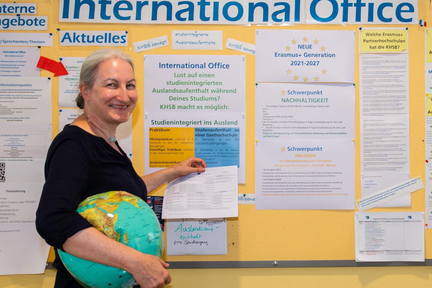 Dr. Marion Bonillo bringt einen Aushang an der Pinnwand des International Office an.