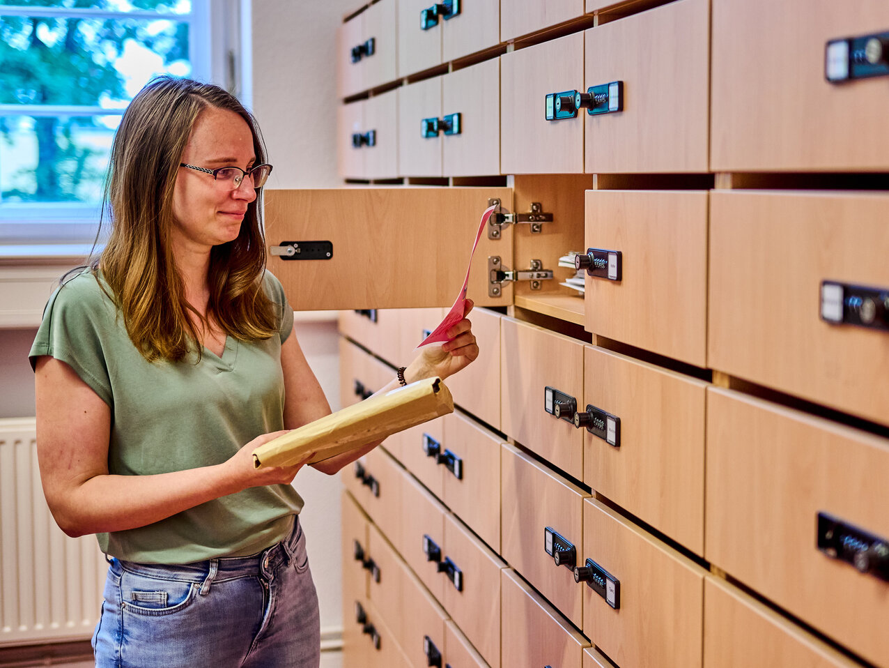 Eine Mitarbeiterin der KHSB steht an ihrem geöffneten Postfach und holt ihre Post heraus.