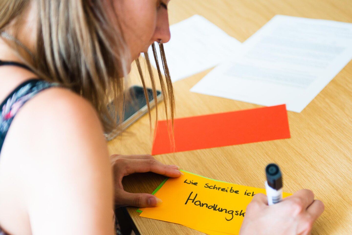 Eine Studentin beschriftet eine Moderationskarte.