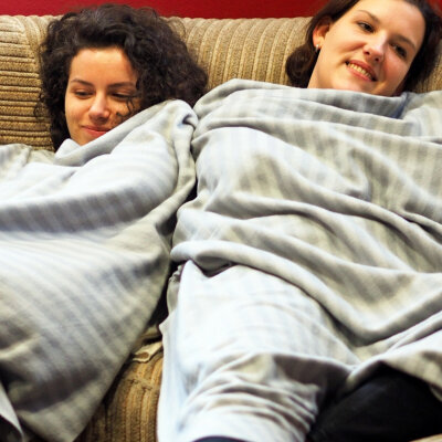 Studierende liegen in Decken eingemurmelt auf einer Couch