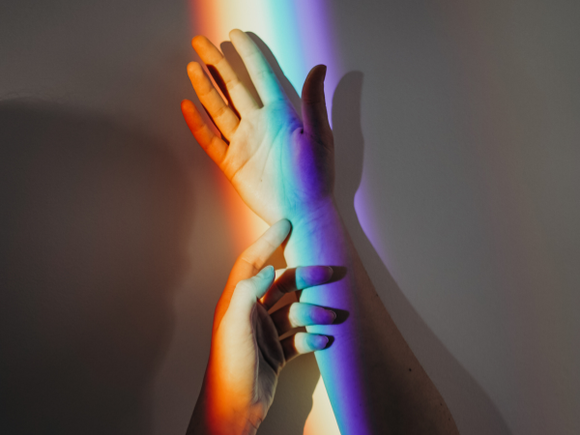 Regenbogenfarben reflektiert auf Händen