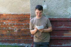 Ein Student lehnt an der Außenwand des KHSB-Gebäudes und notiert sich etwas auf einem Zettel.