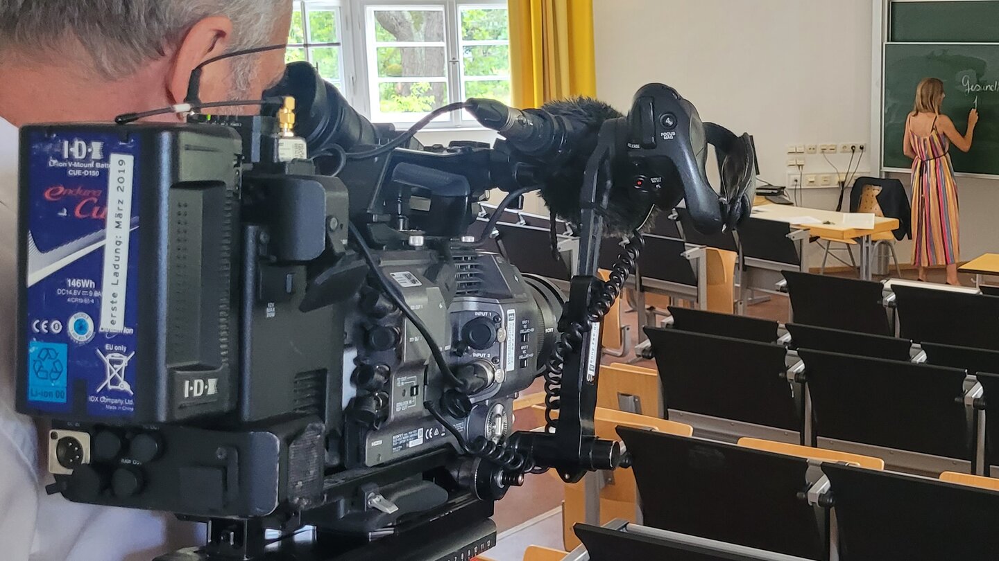 Kameramann filmt Professorin an der Tafel im Hörsaal