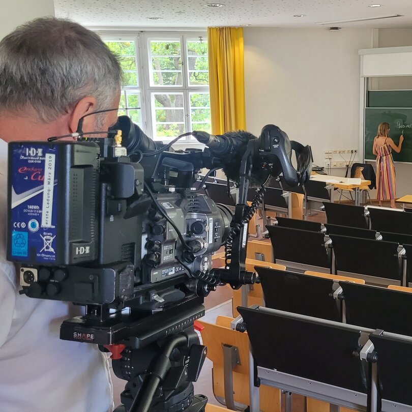 Kameramann filmt Professorin an der Tafel im Hörsaal