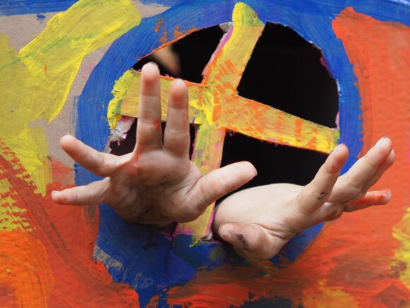 Hände greifen durch bemalten Pappkarton